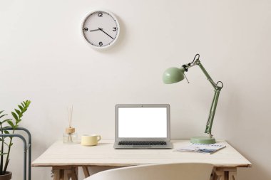 Işık duvarının yanında dizüstü bilgisayarı, lambası ve dekoru olan modern işyeri