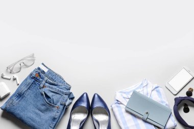 Hafif arka planda kadın giysileri, aksesuarlar ve cep telefonu