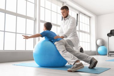 Fizyoterapist rehabilitasyon merkezinde bir çocukla çalışıyor.