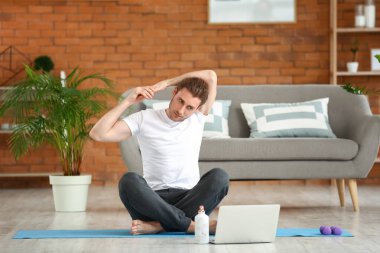 Genç adam evde yoga yapıyor.