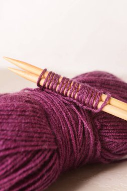 Hafif arkaplanda mor örgü ipliği ve iğneler