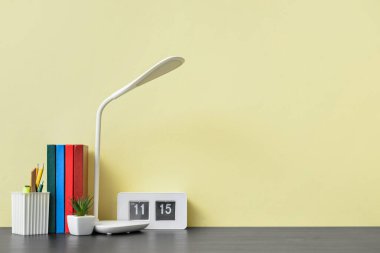Modern lamba, not defterleri ve renk duvarına yakın kırtasiye malzemesi olan şık bir iş yeri