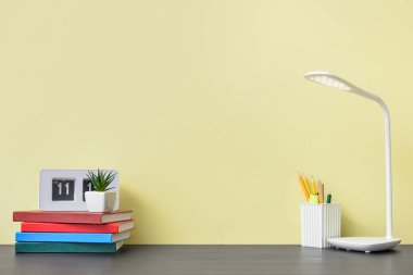 Modern lamba, not defterleri ve renk duvarına yakın kırtasiye malzemesi olan şık bir iş yeri