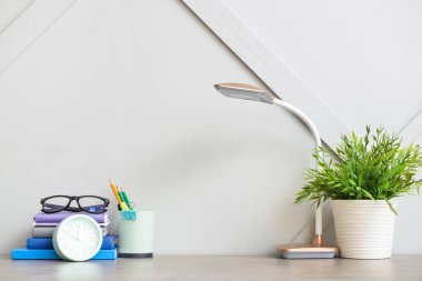 Modern lamba, defterler ve ışık duvarının yanındaki kırtasiye malzemeleriyle şık bir iş yeri.