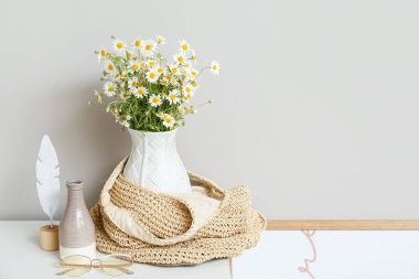 Lamba duvarının yanındaki masa üzerinde papatya ve dekor olan vazo.