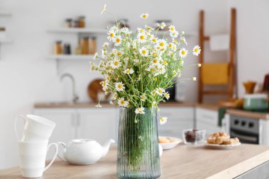 Mutfaktaki masada papatya çayı olan vazo.