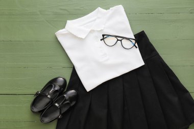 Gözlüklü ve tahta arka planda ayakkabılı şık okul üniforması.