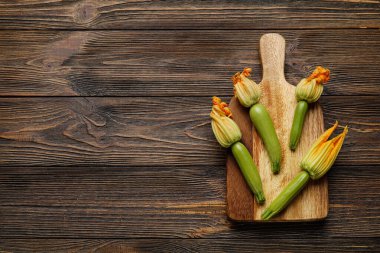 Tahtada taze kabak ve ahşap arka planda çiçekler var.