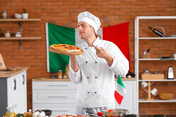 Italian chef with delicious pizza in kitchen