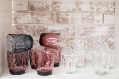 Tuğla duvarın yanındaki rafta boş bardaklar.