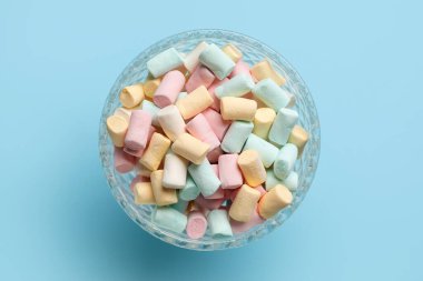 Mavi arka planda şekerleme olan cam kase.