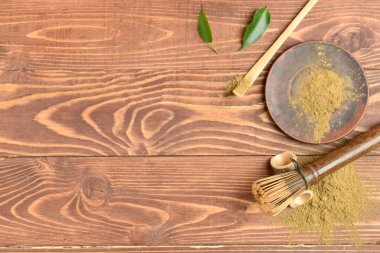 Ahşap arka planda pudralanmış kibrit çayı, chasen ve chashaku karışımı.