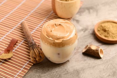 Bir bardak lezzetli dalgona hojicha ve ahşap arka planda chasen.