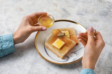Kadın hafif arka planda ballı lezzetli kızarmış ekmek hazırlıyor.