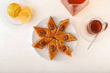 Lezzetli baklava tabağı ve hafif ahşap zemin üzerinde bir bardak Türk çayı.