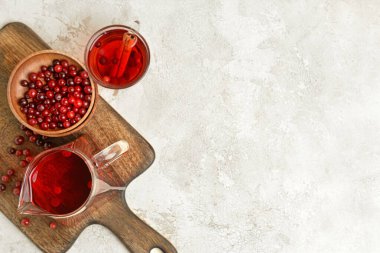 Hafif arkaplanda kızılcık olan bir sürahi ve bir fincan lezzetli çay