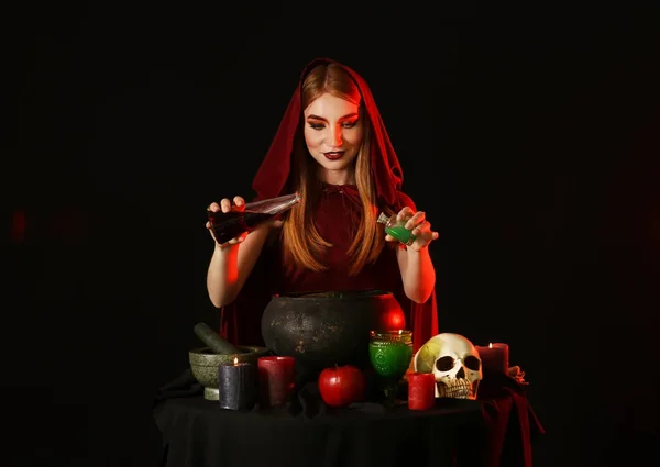 Witch performing ritual on dark background