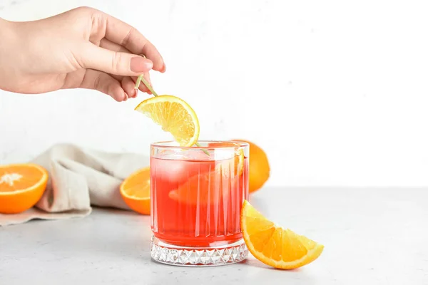 Kobieta Dekorująca Szklankę Smacznego Koktajlu Negroni Pomarańczą Jasnym Tle Zbliżenie — Zdjęcie stockowe
