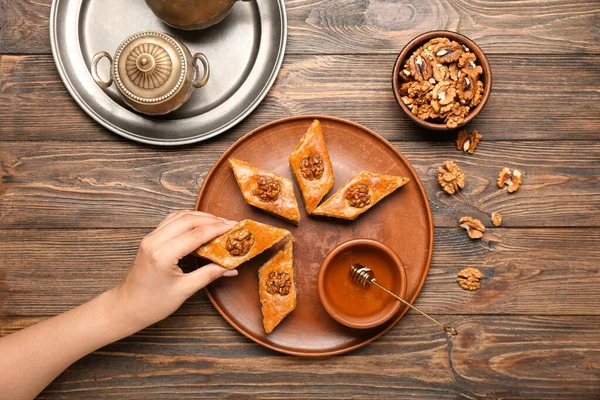 Ahşap Arka Planda Tabaktan Lezzetli Baklava Alan Bir Kadın — Stok fotoğraf