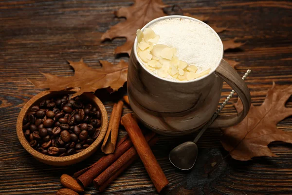 木製の背景においしいアーモンドラテとコーヒー豆のカップ — ストック写真