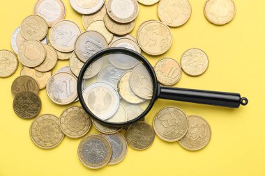 Renk arkaplanında bozuk paralar olan büyüteç