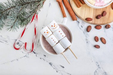 Yumuşak şekerlerden yapılmış kardan adamlar ve beyaz arka planda bir fincan sıcak çikolata.