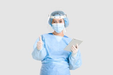 Tabletli kadın Asyalı cerrahın portresi açık arkaplanda baş parmak gösteriyor.