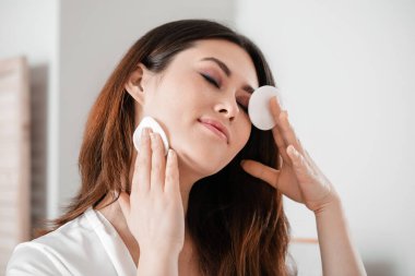 Güzel genç Asyalı kadın evde makyaj yapıyor.