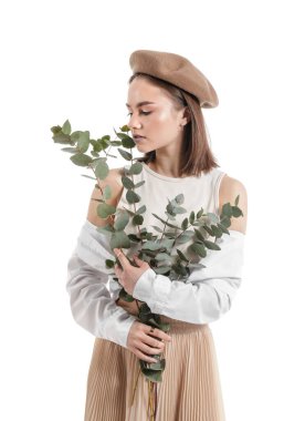 Beyaz arka planda okaliptüs dalları olan güzel genç bir kadın.