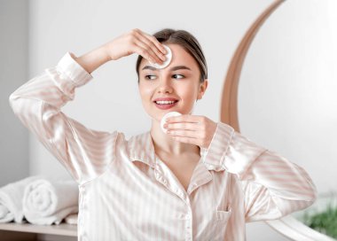 Güzel genç bayan evde makyajı temizliyor.