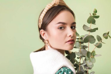 Renkli arka planda okaliptüs dalları olan güzel genç bir kadın.