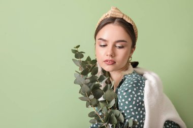 Renkli arka planda okaliptüs dalları olan güzel genç bir kadın.