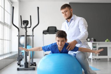 Fizyoterapist rehabilitasyon merkezinde bir çocukla çalışıyor.