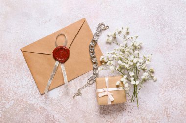 Zarfın içinde çiçekler, kutu ve bilezik var.