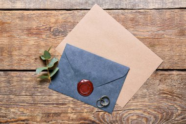 Tahta zemin üzerinde kart ve alyanslar olan zarf