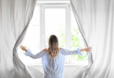Modern odada perdeleri açan kadın