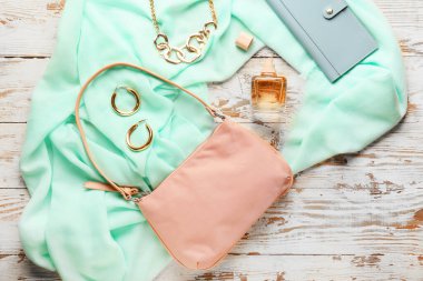 Şık kadın aksesuarları ve hafif ahşap arka planda bir şişe parfüm.