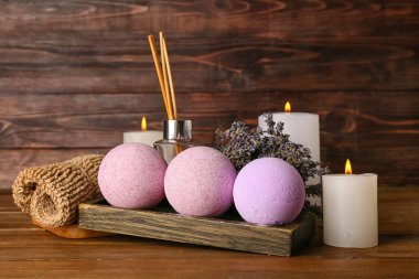 Güzel bir spa kompozisyonu, banyo bombaları, yanan mumlar ve ahşap arka planda lavanta çiçekleri.