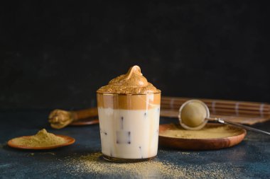 Koyu arkaplanda bir bardak lezzetli dalgona hojicha.