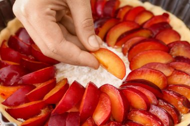 Kadın masada erikli turta pişiriyor, yakın plan.