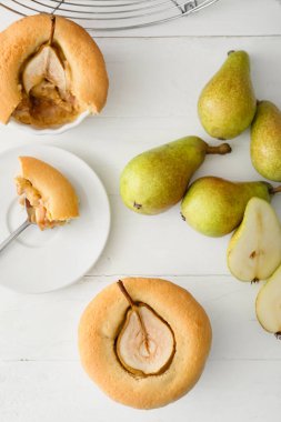 Lezzetli armutlu turtalar ve hafif ahşap arka planda taze meyveler.