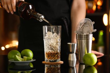 Bayan barmen bardaki masada ferahlatıcı Long Island buzlu çayı yapıyor.