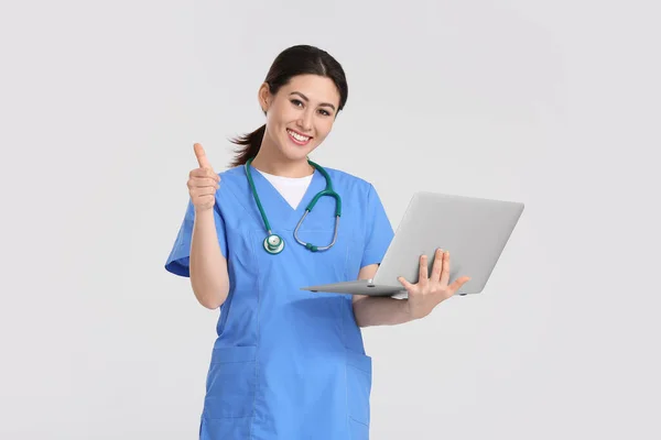 亚洲女医生的画像 手提电脑在浅色背景下显示大拇指 — 图库照片