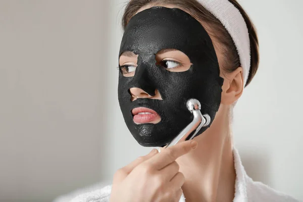 Mooie Jonge Vrouw Met Vel Gezichtsmasker Massage Tool Thuis — Stockfoto