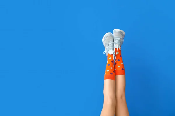 Legs of beautiful woman in socks and casual shoes on color background