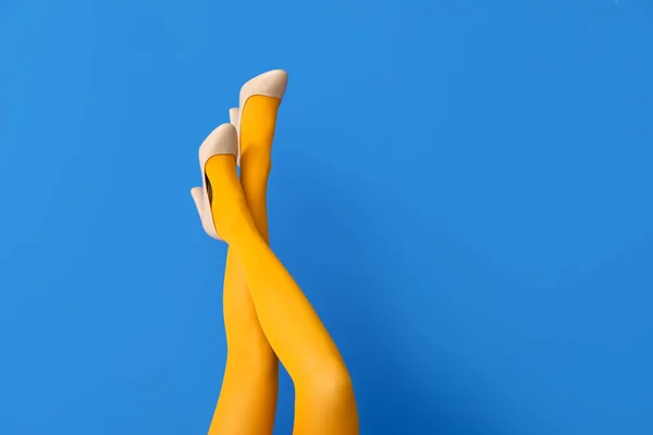 色の背景にタイツとハイヒールの靴で美しい若い女性の脚 — ストック写真