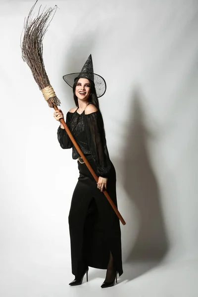 浅色底色扫帚的年轻女巫 — 图库照片