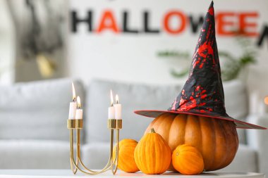 Cadılar Bayramı balkabakları, cadı şapkası ve mumlar odada.