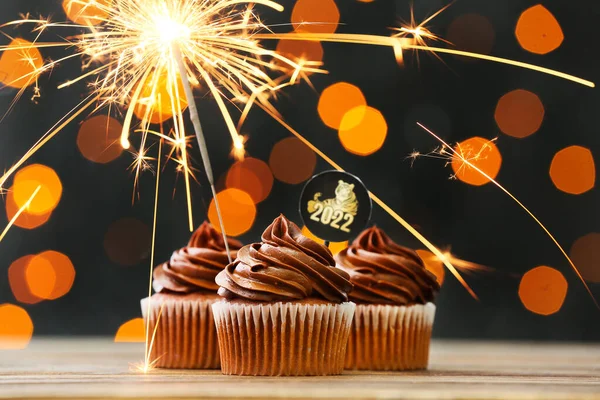 2022年新年庆祝的美味纸杯蛋糕 桌上闪烁着火花 灯火通明 — 图库照片