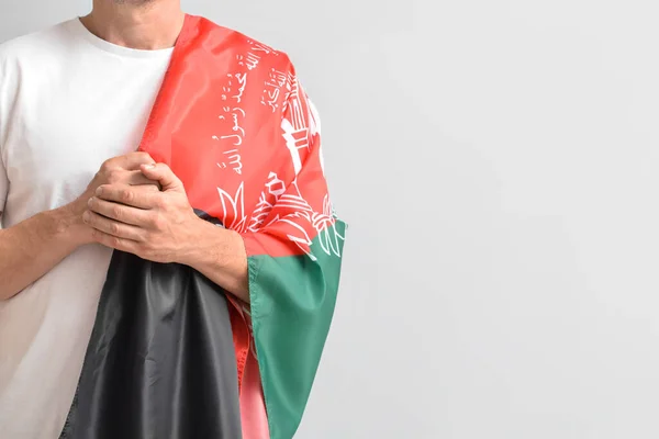 Man with flag of Afghanistan on light background